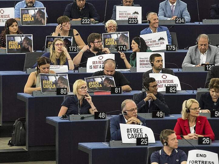 "Seenotrettung ist kein Verbrechen" - Mitglieder des EU-Parlaments zeigen Schilder zur Unterstützung der Kapitänin des Rettungsschiffes "Sea-Watch 3".