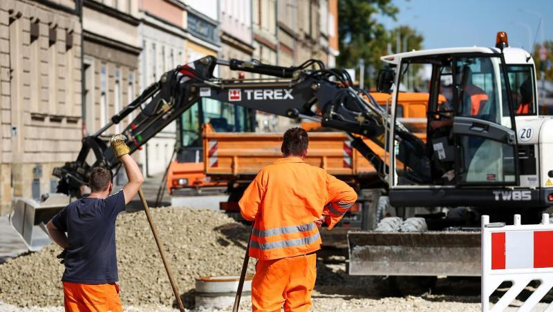 Zwei Bauarbeiter und ein Kollege in einem Bagger beim Verteilen von Kies an einer Baustelle. Foto: David Ebener/Archiv Zwei Bauarbeiter und ein Kollege in einem Bagger beim Verteilen von Kies an einer Baustelle. Foto: David Ebener/Archiv