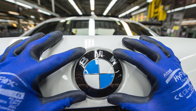 Höchst profitabel: Ein Mitarbeiter montiert ein BMW-Emblem auf den Kofferraumdeckel eines Fahrzeugs der 7er Reihe. Höchst profitabel: Ein Mitarbeiter montiert ein BMW-Emblem auf den Kofferraumdeckel eines Fahrzeugs der 7er Reihe.
