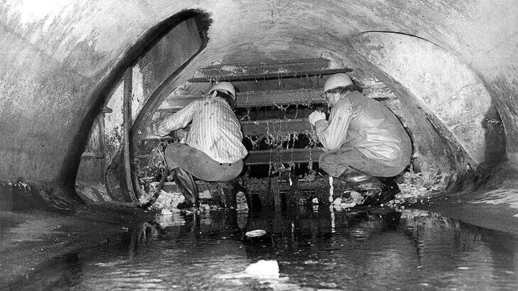 Hunderte Menschen fliehen durch die unterirdische Kanalisation von Ost- nach West-Berlin, bis der Einbau von Gittern (hinten) neue Wege erzwingt. Hier ein Foto aus dem Jahr 1990, auf dem Arbeiter die letzten dieser Fluchtgitter entfernen.
