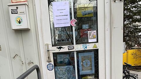 Letzte Blumengrüße, weiße und rote Grablichter schmücken den Eingang zum Kiosk am Romanplatz 1.