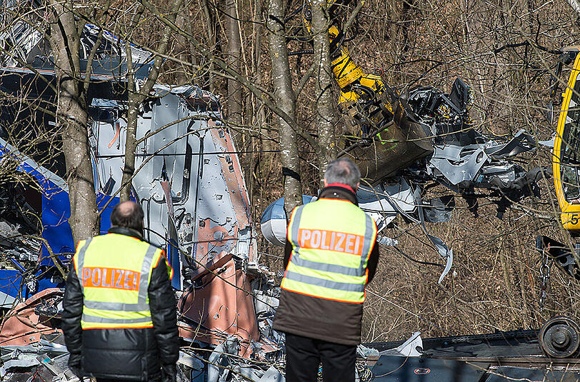 Ermittler der Polizei stehen vor einem der vollkommen zerstörten Waggons.