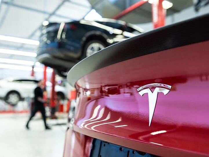 Das Logo des Fahrzeugherstellers Tesla auf einem Fahrzeug in einem Tesla Service Center.