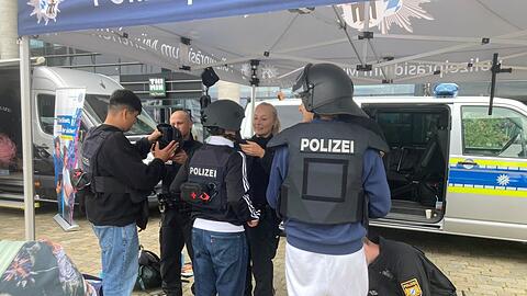 Eres, Marcel und Rubenprobierenneugierig die Schutzausrüstung der Münchner Polizei an, auch die Schusswesten. "Ganz schön schwer", finden sie.