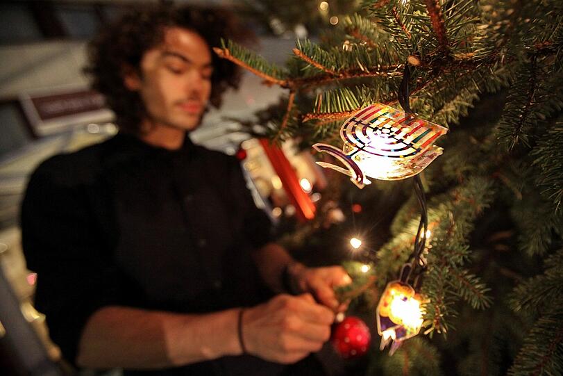 Der Geschäftsführer des Café Leonar, Arnold Simmenauer, schmückt am Mittwoch (21.12.2011) vor seinem Cafe in Hamburg einen «Weihnukka»-Tannenbaum mit jüdischem Weihnachtsschmuck.