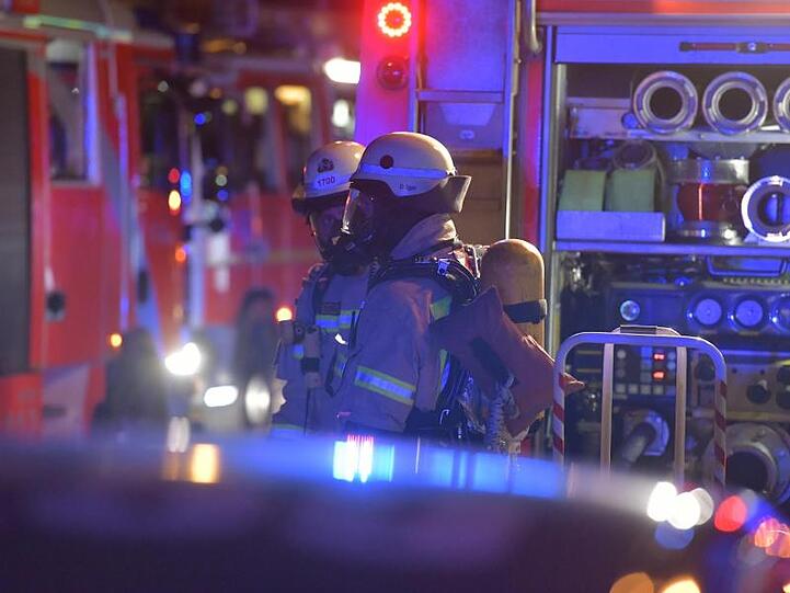 Feuerwehrleute stehen vor Einsatzfahrzeugen. Foto: Paul Zinken/Archiv