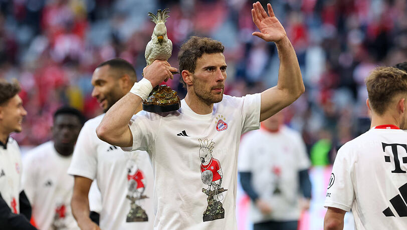 Ein Bayern-Profi feiert mit dem Team-Maskottchen Kakadu in der Hand und Meistershirt auf dem Rasen der Allianz Arena die 35. Meisterschaft nach dem 4:2 gegen Stuttgart.