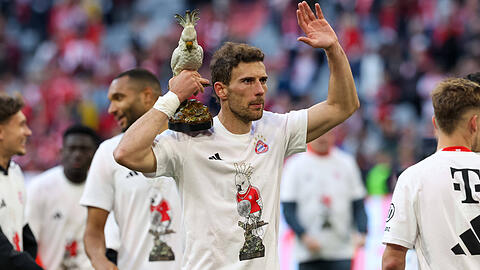 Ein Bayern-Profi feiert mit dem Team-Maskottchen Kakadu in der Hand und Meistershirt auf dem Rasen der Allianz Arena die 35. Meisterschaft nach dem 4:2 gegen Stuttgart.