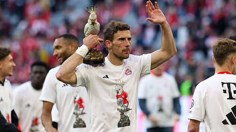 Ein Bayern-Profi feiert mit dem Team-Maskottchen Kakadu in der Hand und Meistershirt auf dem Rasen der Allianz Arena die 35. Meisterschaft nach dem 4:2 gegen Stuttgart.