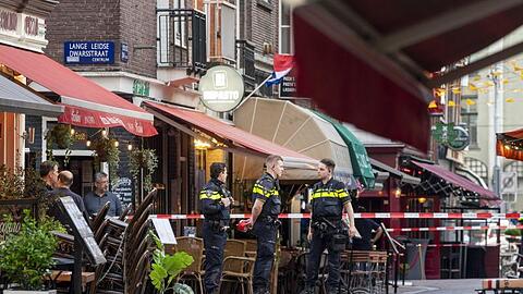 Polizisten ermitteln im Zentrum von Amsterdam, nachdem ein Unbekannter auf den Reporter schoss.