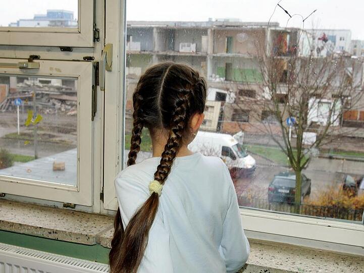 Traurig schaut dieses kleine Mädchen aus dem Fenster