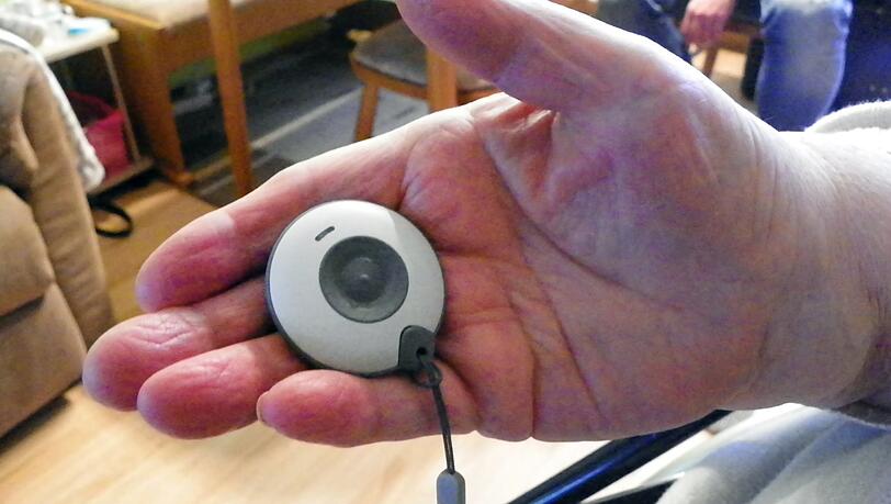 Eine Seniorin hält einen Hausnotruf in der Hand.