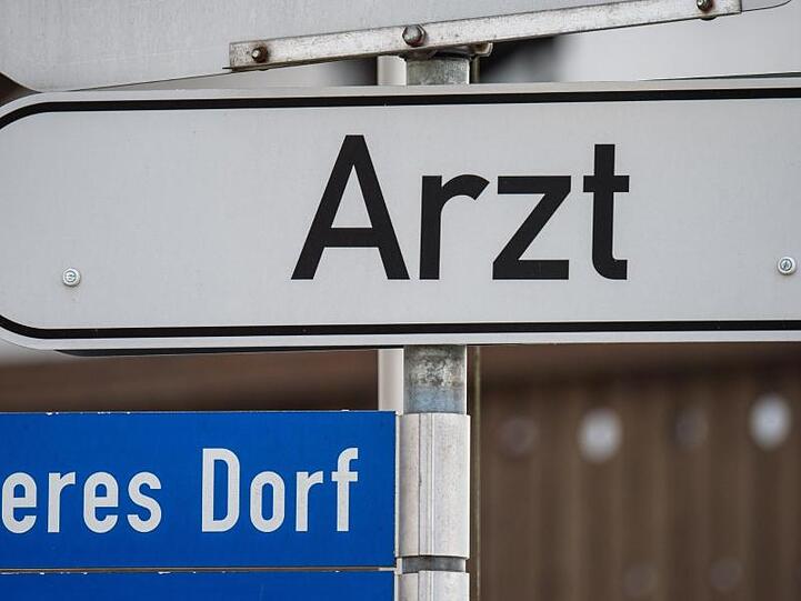 Ein Hinweisschild mit der Aufschrift "Arzt" ist in einem kleinen Ort angebracht.