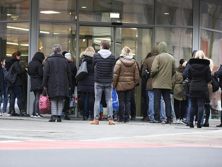 Menschen warten vor der Öffnung einer Aldi-Filiale vor dem Eingang..