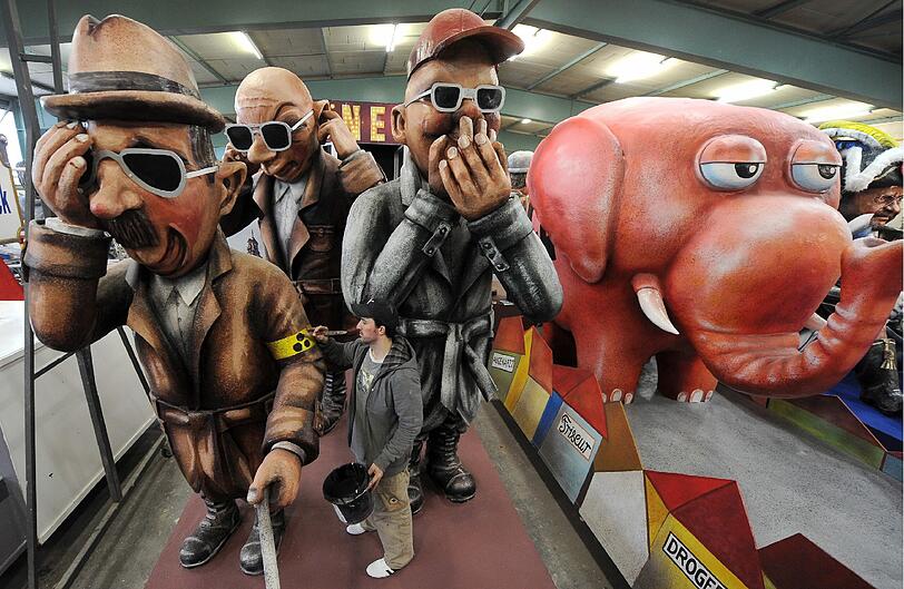 Ein Wagenbauer des Mainzer Carneval-Vereins (MCV) nimmt am Dienstag in der Wagenhalle des Vereins in Mainz am Motivwagen "V-Leute" letzte Arbeiten vor, der drei Verfassungsschutz-Agenten zeigt, die nichts sehen, nichts hören und nichts sagen.