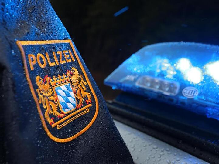 Ein bayerischer Polizist steht vor einem Streifenwagen. Foto: Karl-Josef Hildenbrand/Archivbild