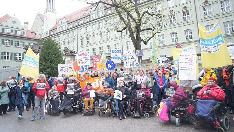 "Braucht's jetzt einen Fuß-Entscheid?", fragt eines der Demo-Schilder. Viele bringen auch Fotos von zugeparkten Gehsteigen mit zur Ettstraße, um zu zeigen, vor welch schwierigen Situationen sie im Alltag stehen – gerade auch, wenn man mit Rollstuhl unterwegs ist.