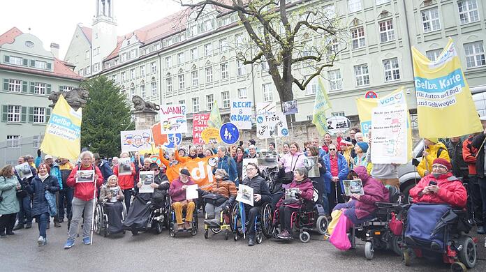 "Braucht's jetzt einen Fuß-Entscheid?", fragt eines der Demo-Schilder. Viele bringen auch Fotos von zugeparkten Gehsteigen mit zur Ettstraße, um zu zeigen, vor welch schwierigen Situationen sie im Alltag stehen – gerade auch, wenn man mit Rollstuhl unterwegs ist.