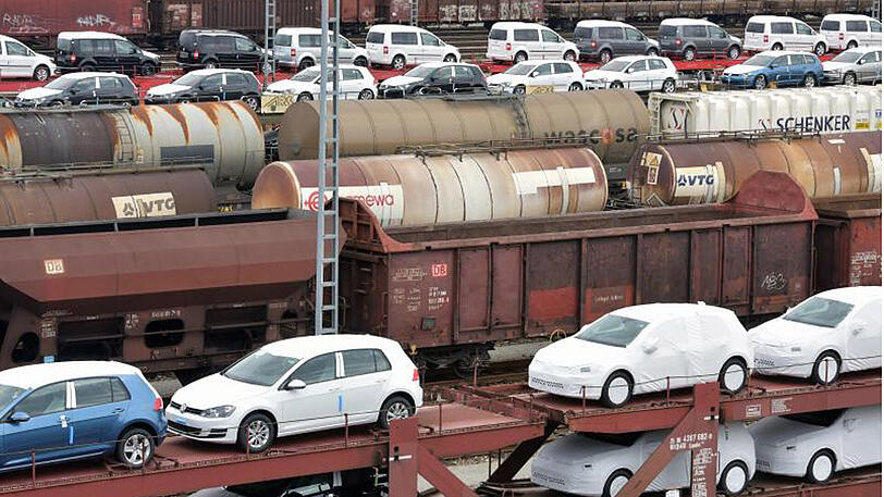 Güterwagen der Bahn, beladen mit Neuwagen, stehen auf einem Rangierbahnhof.
