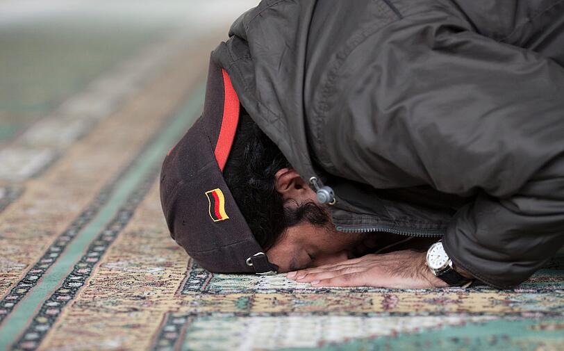 Ein gläubiger Moslem kniet auf einem Teppich in einer Moschee und betet.