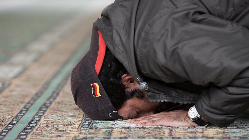 Ein gläubiger Moslem kniet auf einem Teppich in einer Moschee und betet. Ein gläubiger Moslem kniet auf einem Teppich in einer Moschee und betet.