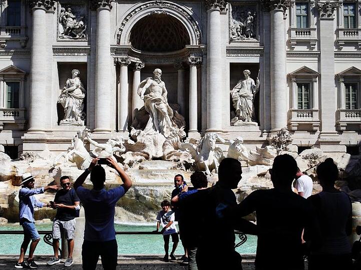 Touristen fotografieren den Trevi-Brunnen in Rom. Angesichts steigender Infektionszahlen wappnen sich manche Länder mit neuen Regeln.