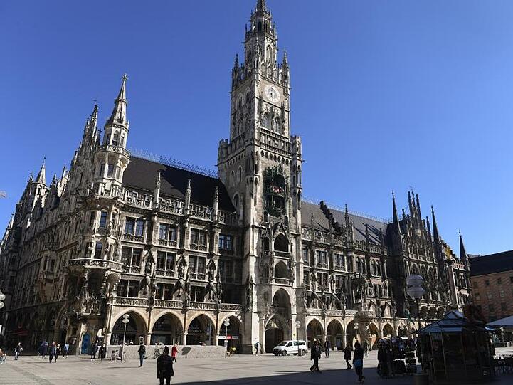 Vereinzelt gehen Menschen vor dem Rathaus über den Marienplatz. Foto: Felix Hörhager/dpa/Archivbild