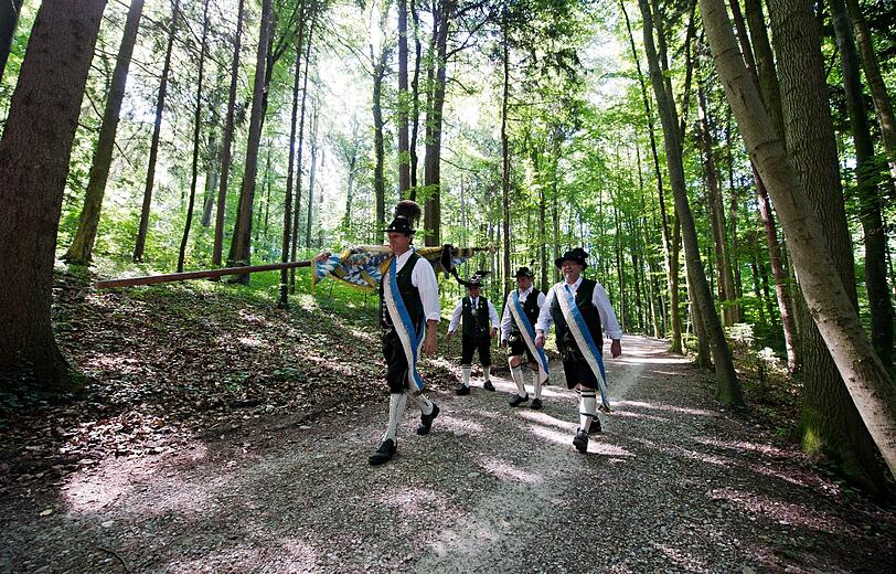 Männer in Trachten gehen  in Berg (Bayern) durch ein Waldstück. Die "Königstreuen" kamen an der Votivkapelle im Schlosspark bei Berg zu einer Gedenkfeier anlässlich des 128. Todestages von König Ludwig II. zusammen.