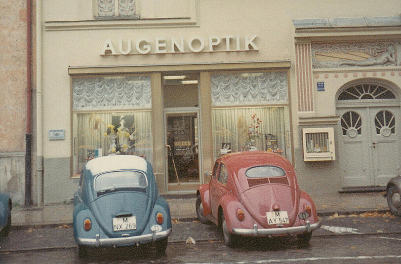 Der Optiker Riess an selber Stelle vor Jahrzehnten: Alte Käfer parken davor und ein Zigarettenautomat hängt rechts daneben.