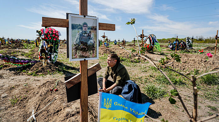 Alexander sitzt vor dem Grab seines älteren Bruders und Soldaten Evgeny Ketov, der im März während der russischen Invasion in der Region Donezk im Donbass ums Leben gekommen ist.