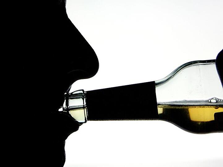 Die Silhouette eines Alkohol trinkenden Mannes. Foto: Arno Burgi/Archivbild