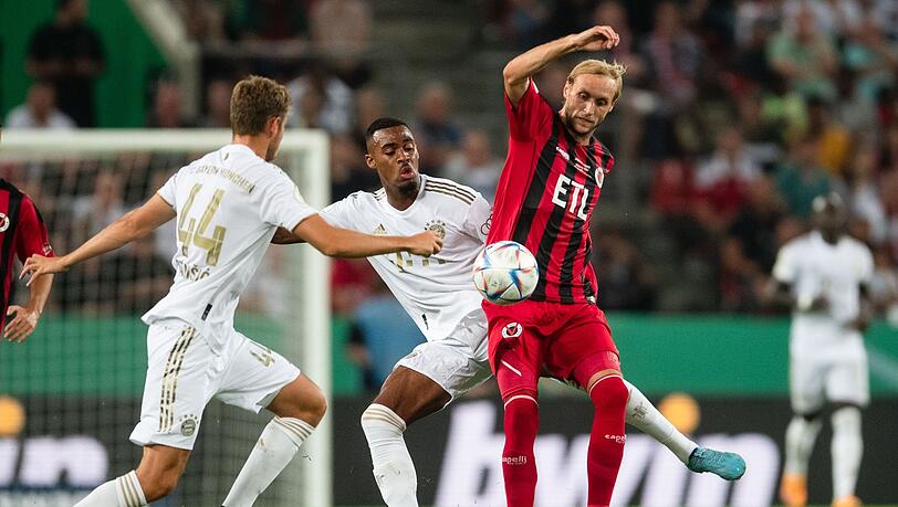 Kölns Marcel Risse (r) und Bayerns Ryan Gravenberch (M) kämpfen um den Ball. Links ist Bayerns Josip Stanisic.