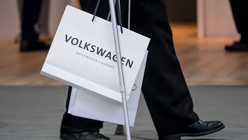 Ein Aktionär mit Krücken trägt vor Beginn der Hauptversammlung der Volkswagen AG eine Volkswagentüte. Milliardengewinne, Rekordabsatz, ein Chefwechsel und die Diesel-Misere: Der weltgrößte Autobauer Volkswagen sorgt für gemischte Gefühle bei seinen Aktionären.