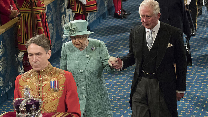 Setzte die Krone im Parlament nicht auf: Die Queen an der Hand von Prinz Charles Setzte die Krone im Parlament nicht auf: Die Queen an der Hand von Prinz Charles