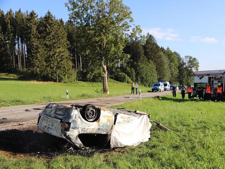 Feuerwehrleute neben dem ausgebrannten Unfallwrack bei Aitrang. Foto: Davor Knappmayer/dpa
