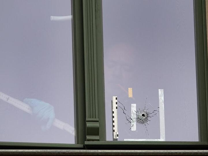 Ein Beamter der Spurensicherung untersucht ein Loch in einem Fenster in einem Haus gegenüber der Synagoge in Halle.