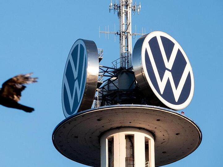 Zwei Vögel fliegen vor dem Logo der Volkswagen AG auf dem VW-Tower. Foto: David Hutzler/dpa/Archivbild