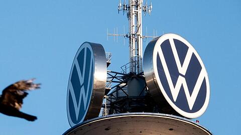 Zwei Vögel fliegen vor dem Logo der Volkswagen AG auf dem VW-Tower. Foto: David Hutzler/dpa/Archivbild
