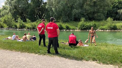 Männer mit "Sicherheitsdienst"-T-Shirts sprechen Frauen ohne Bikini-Oberteil an der Isar an.