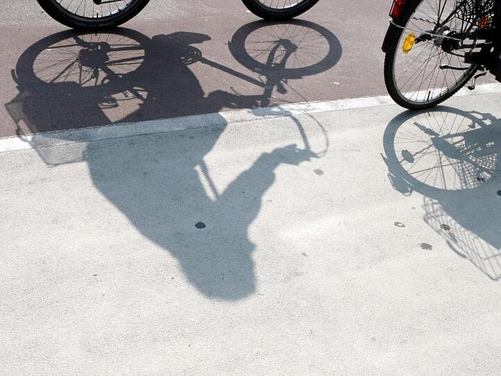 Radfahrer werfen Schatten auf einem Fahrradweg. Foto: Ronald Wittek/Archiv