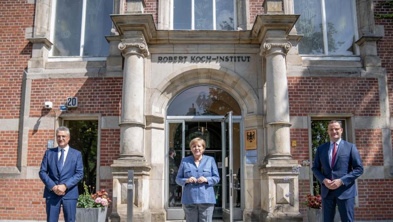 RKI-Präsident Lothar Wieler, Bundeskanzlerin Angela Merkel und Bundesgesundheitsminister Jens Spahn vor dem Eingang zum Robert Koch-Institut.