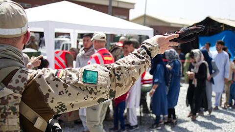 Soldaten und Helfer verteilen Spenden an Menschen, die auf dem Flughafen von Kabul auf eine Ausreisemöglichkeit warten.
