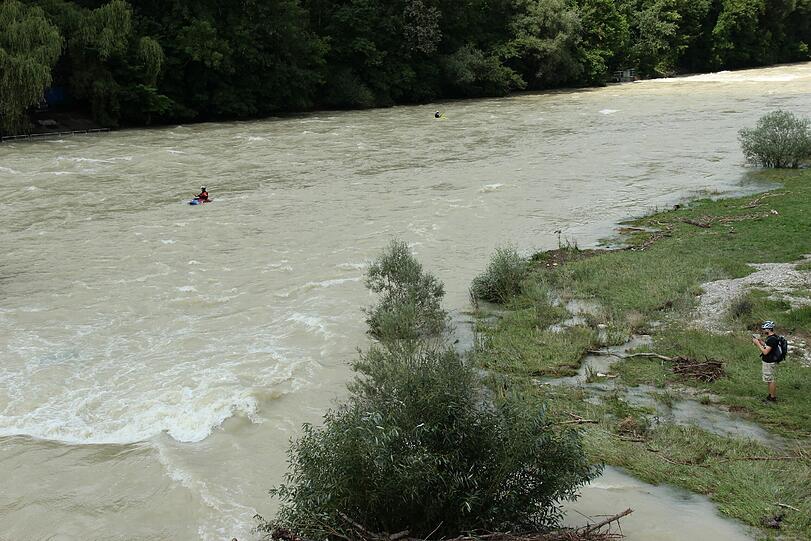 Hochwasser für die einen, perfekte Wellen für die anderen. Waghalsig tummeln sich Sportler in der Isar.