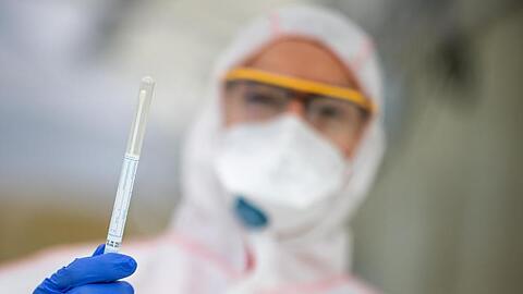 Ein Mitarbeiter hält in einem Abstrichzentrum einen Coronatest-Abstrich in der Hand. Foto: Sebastian Gollnow/dpa/Symbolbild