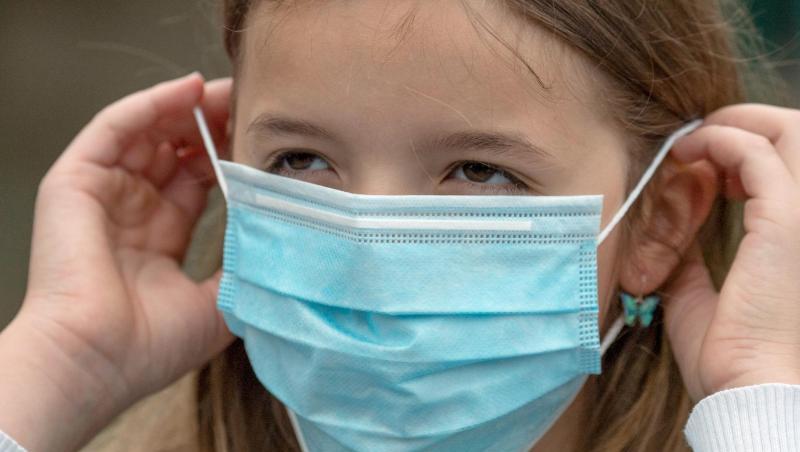 Eine Schülerin setzt sich vor dem Betreten eines Schulgeländes in Frankfurt am Main eine Einweg-Maske auf. Eine Schülerin setzt sich vor dem Betreten eines Schulgeländes in Frankfurt am Main eine Einweg-Maske auf.