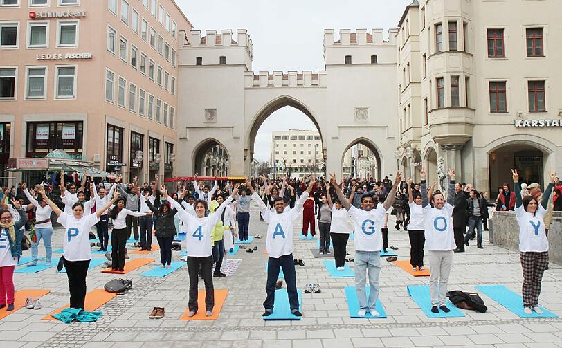Hopsen und Dehnen in der Fußgängerzone: Am Stachus haben sich Yoga-Fans zu einem Flashmob unter freiem Himmel verabredet. Die Bilder.