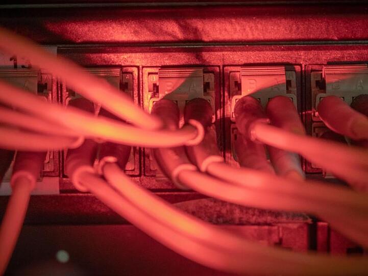 Glasfaserkabel führen zu einem Internet Switch in einem Serverraum. Foto: Michael Kappeler/dpa/Symbolbild