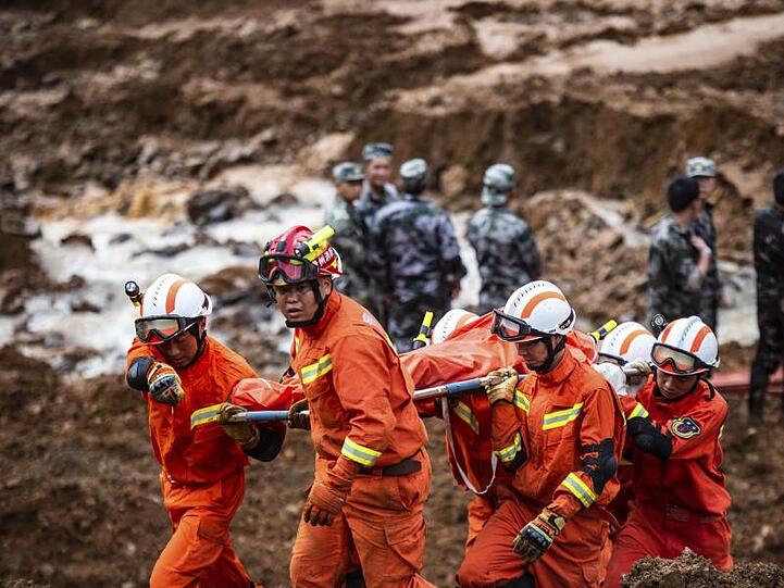 Rettungshelfer tragen eine Leiche. Bei zwei Erdrutschen sind mindestens zwölf Menschen ums Leben gekommen.