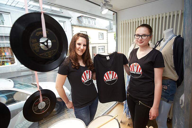Die Stadt hat sich bestens auf die Besucher eingestellt: Katarina (l) und Ann-Kathrin zeigen in einem Bekleidungsgeschäft T-Shirts zum Rockfestival "Rock am Ring".