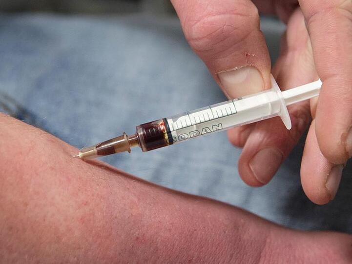 Ein Drogensüchtiger spritzt sich in einem Druckraum Heroin.